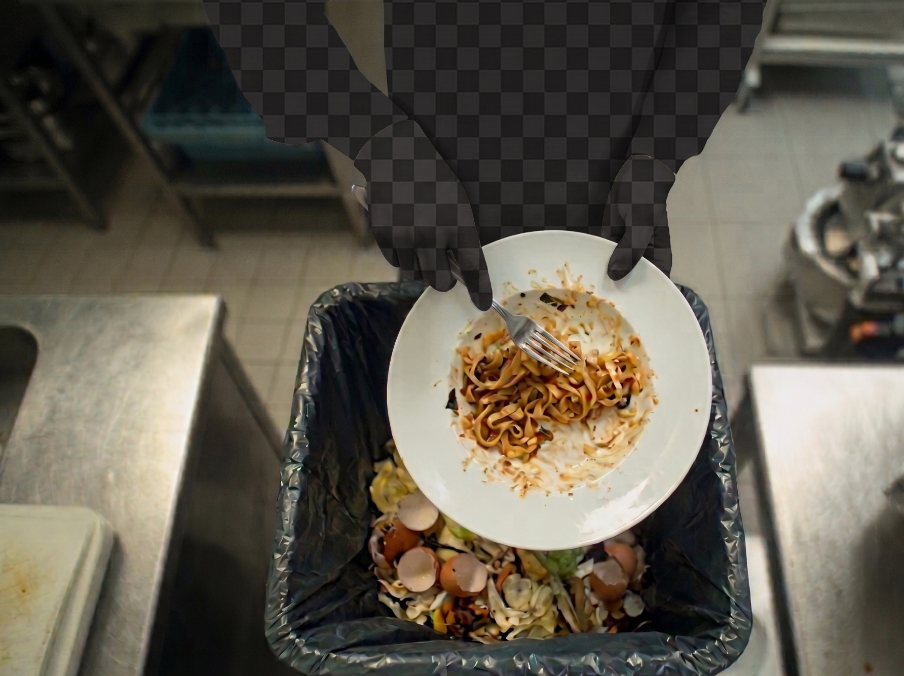 Overhead view of a person (silhouette on a transparent checkered background) scraping a plate of leftover pasta with a fork into a trash bin filled with food scraps and eggshells, in a commercial kitchen.