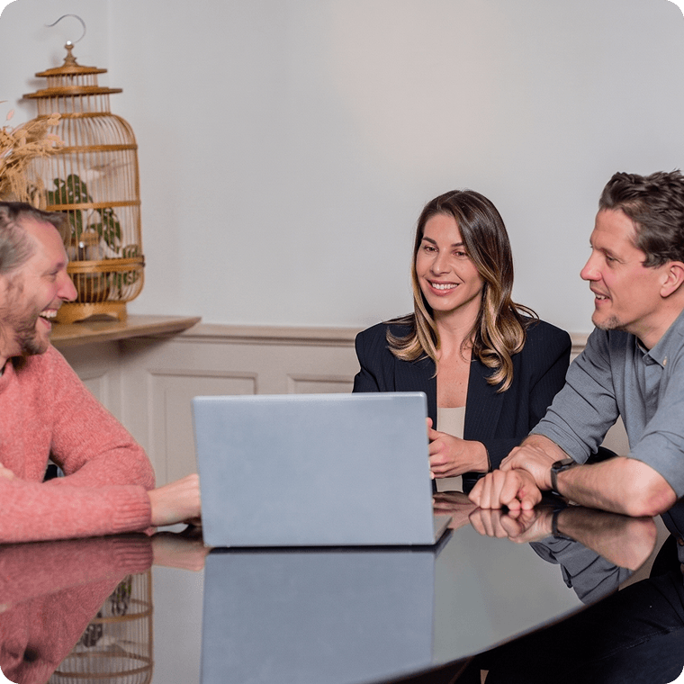 team-meeting-laptop Drie collega's die lachend rond een laptop praten aan een vergadertafel